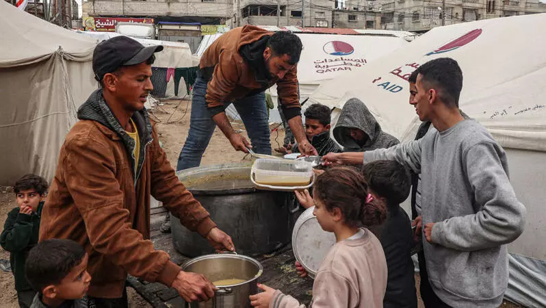 Das Bild zeigt Menschen, die Essen im Freien ausgeben. Helfer verteilen Suppe an hungernde Menschen in der palästinensischen Stadt Rafah im Gazastreifen (18. Februar 2024)